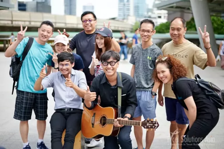 Contestants in the Amazing Race Bangkok, entertaining onlookers with an energetic busking performance.