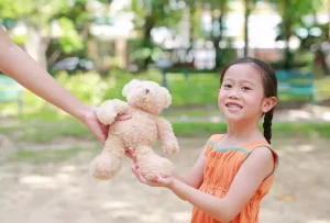 Child being handed a teddy bear