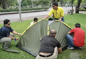 Blindfolded participants working together to erect a tent during a team building exercise in Bangkok, showcasing trust, and problem-solving.