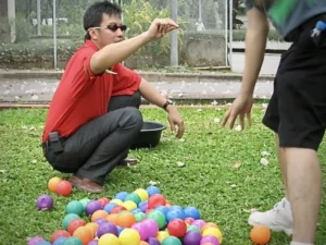 A participant holding colored balls, showcasing focus, dexterity, and engagement in a team building activity in Bangkok.
