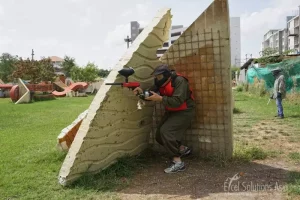 A player skilfully concealing himself behind cover, carefully peering out to take a calculated shot in the Bangkok paintball arena.