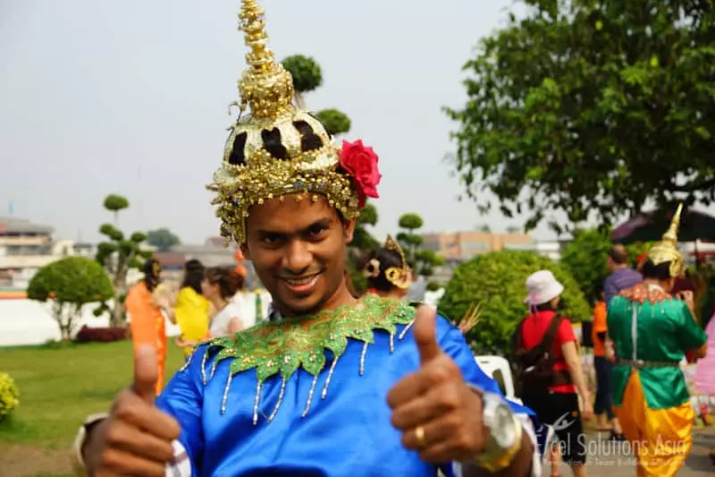 A participants engaging in a cultural challenge while dressed in costume at Wat Arun in Bangkok during our Amazing Race