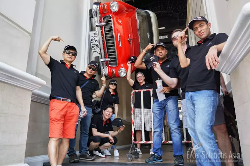 Scavenger Hunts in Pattaya: A red car on a wall along Walking Street while teams pose below it.