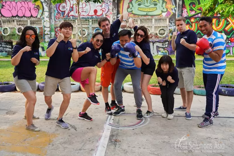 A spirited group engrossed in a lively Thai boxing session, honing their skills and embracing the energetic atmosphere during an Amazing Race Bangkok.