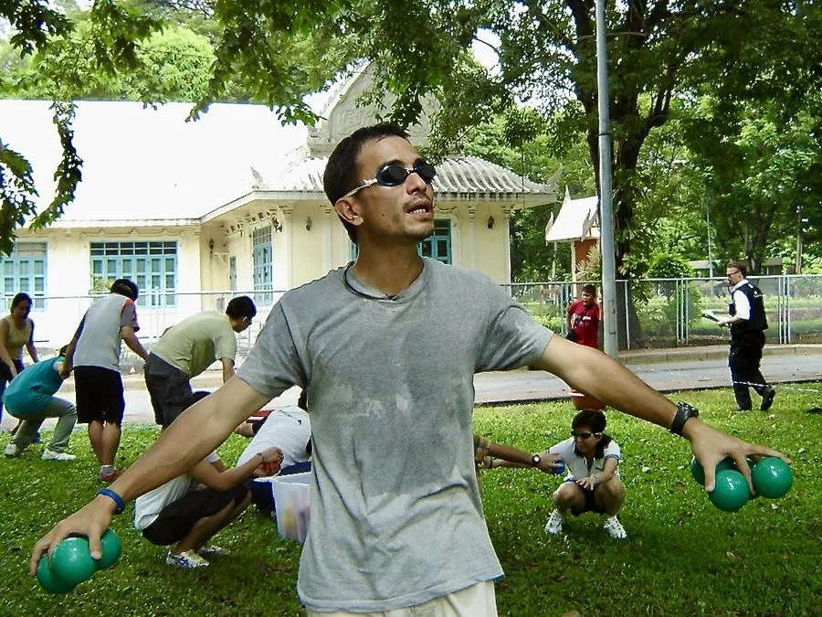 A team member courageously navigating blindfolded while holding coloured balls during a team building activity in Bangkok.